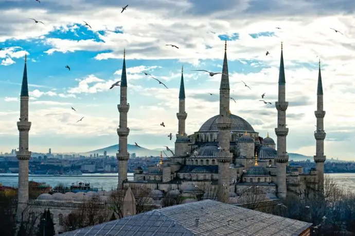 Historic mosque stone building with 4 minarets against a blue sky