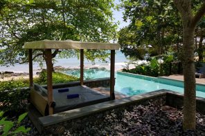 Infinity pool overlooking a beach with a sun lounger in the foreground