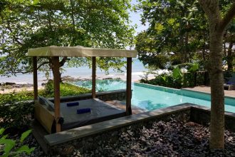 Infinity pool overlooking a beach with a sun lounger in the foreground