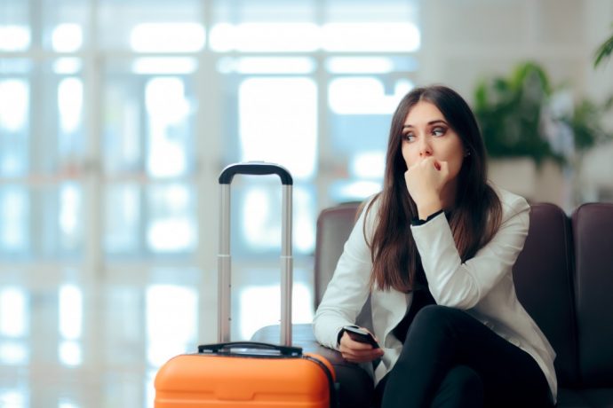 girl with orange suitcase sitting on a bench