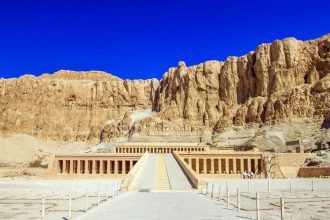 Blue skies with rocky cliff behind the stone temple of Hatshepsut in Egypt