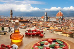 Close up view of olive oil, a plate of tomatoes and cheese, with rooftop views in the background