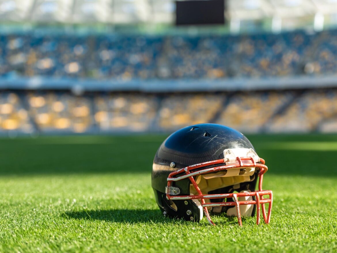 American football helmet on the green grass floor of a stadium