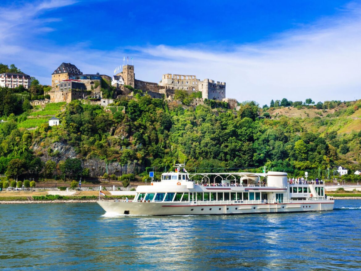 Boat cruising on a river surrounded by lush green riverbanks and a castle in the distance