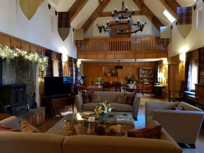 Great hall with wood panelling, sofas, and a chandelier