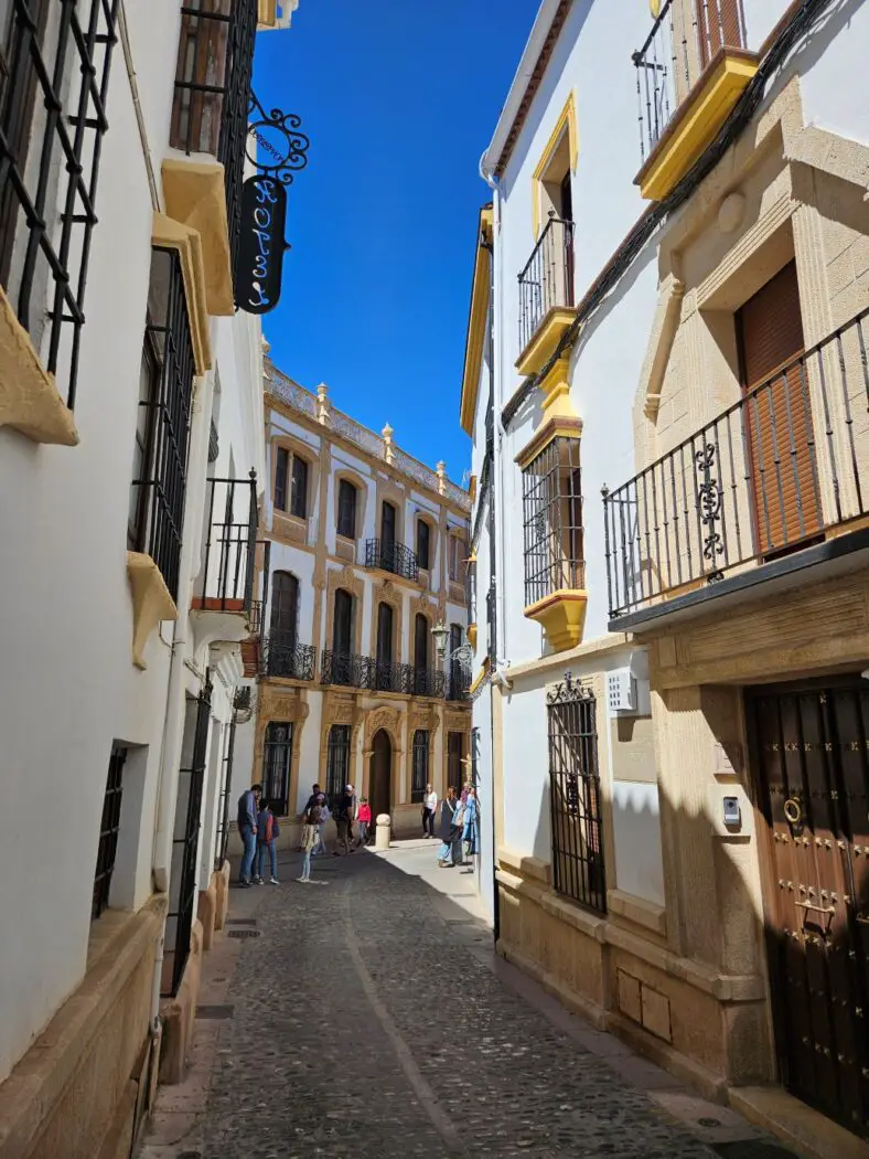 Tall white buildings with yellow window frames lining a cobbled street