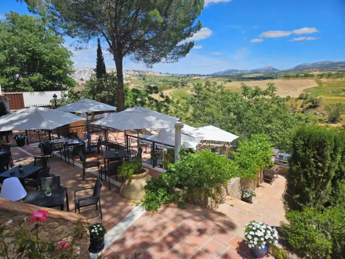 Terrace with tables and umbrellas overlooking green countryside