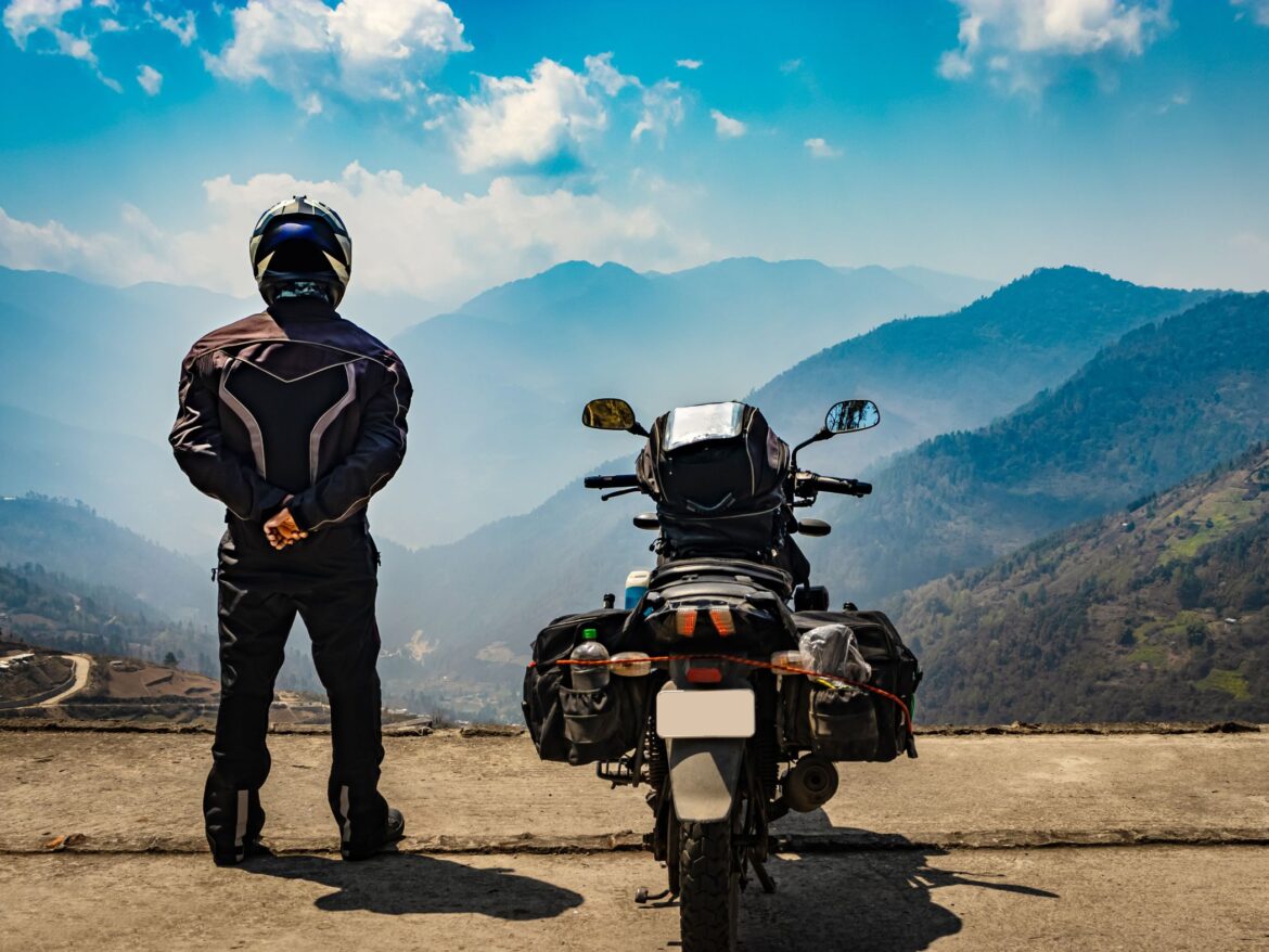 Man standing next to motorbike in the mountains