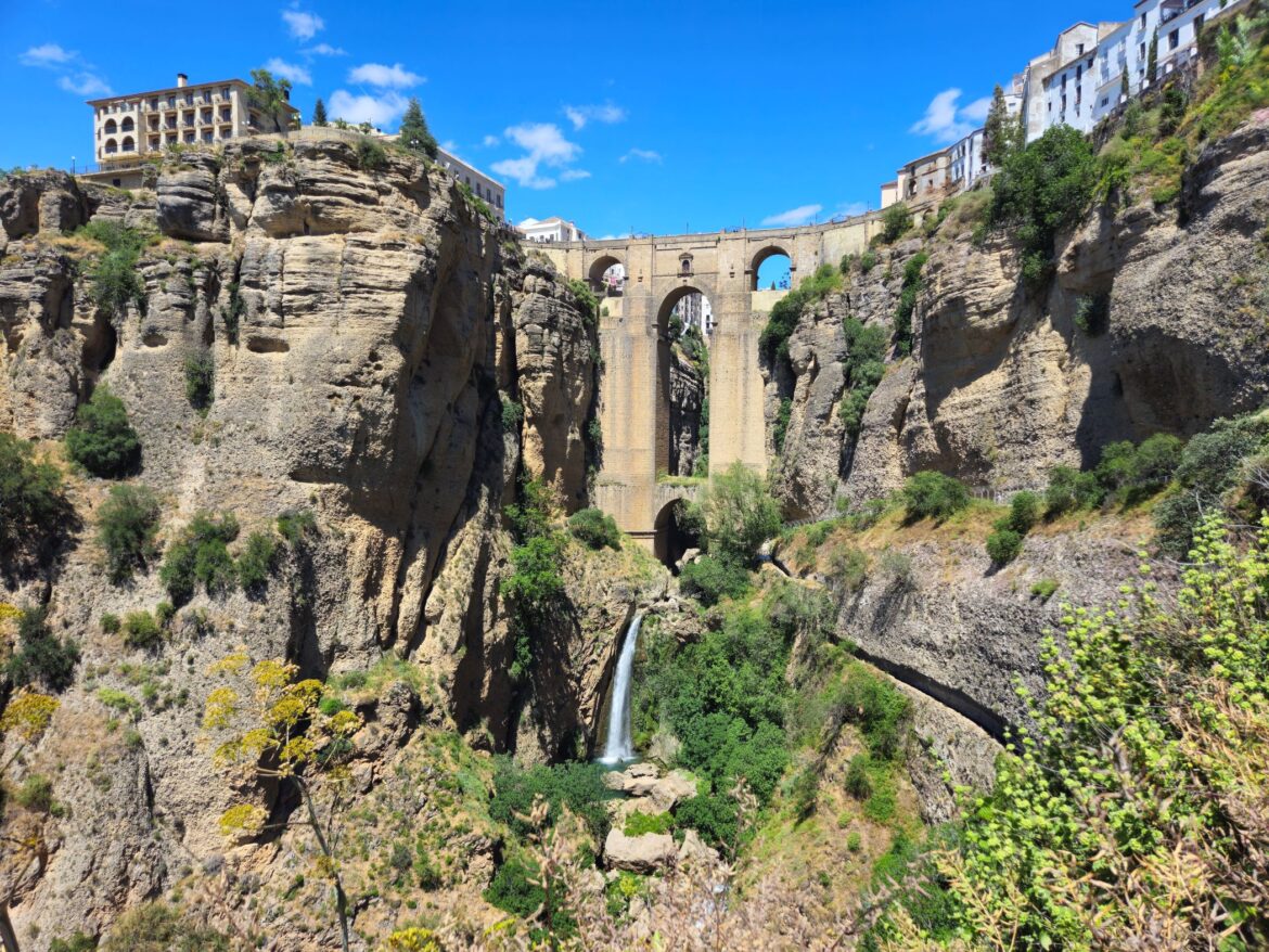 Rocky gorge with tall stone bridge in the middle and a waterfall beneath