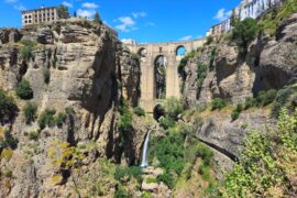 Rocky gorge with tall stone bridge in the middle and a waterfall beneath