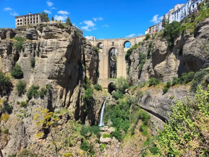 Rocky gorge with tall stone bridge in the middle and a waterfall beneath