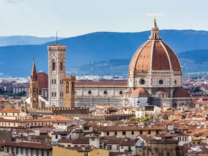 Red city rooftops with a large domed cathedral in the centre