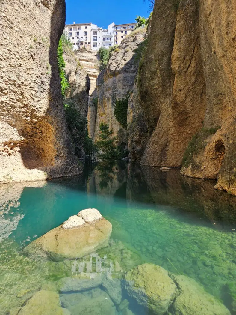 Steep rocky cliffs with turquoise water at the bottom and white houses at the top